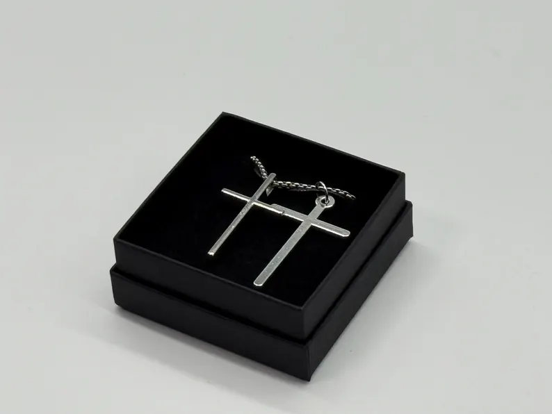 Pair of silver cross pendants on a chain, set in a black gift box, photographed in the Robert Anthony Art home studio