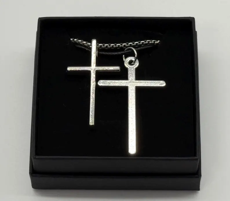 Close view of a matching pair of silver cross pendants in a black gift box