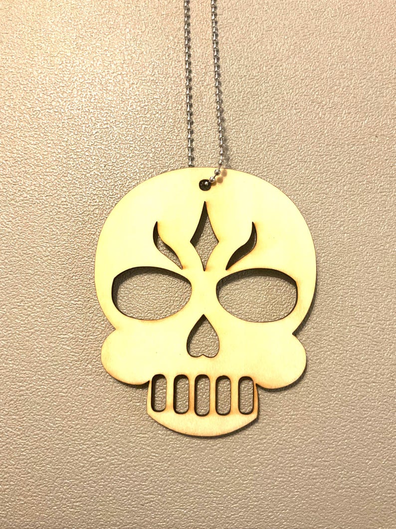Laser cut birch wood sugar skull pendant necklace with cut-out eyes, heart-shaped nose and teeth detail on a stainless ball chain — handmade Halloween jewelry by Robert Anthony Art in Vacaville, California