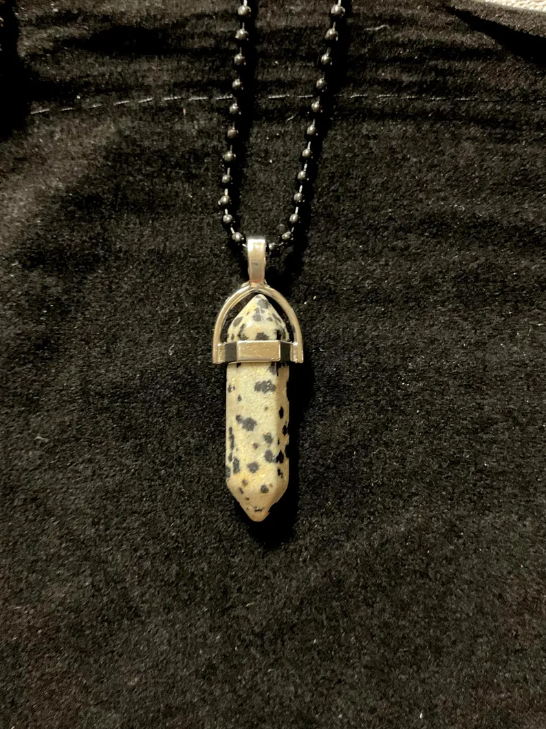 Dalmatian jasper crystal point pendant in a silver setting on a black ball chain, photographed on black velvet