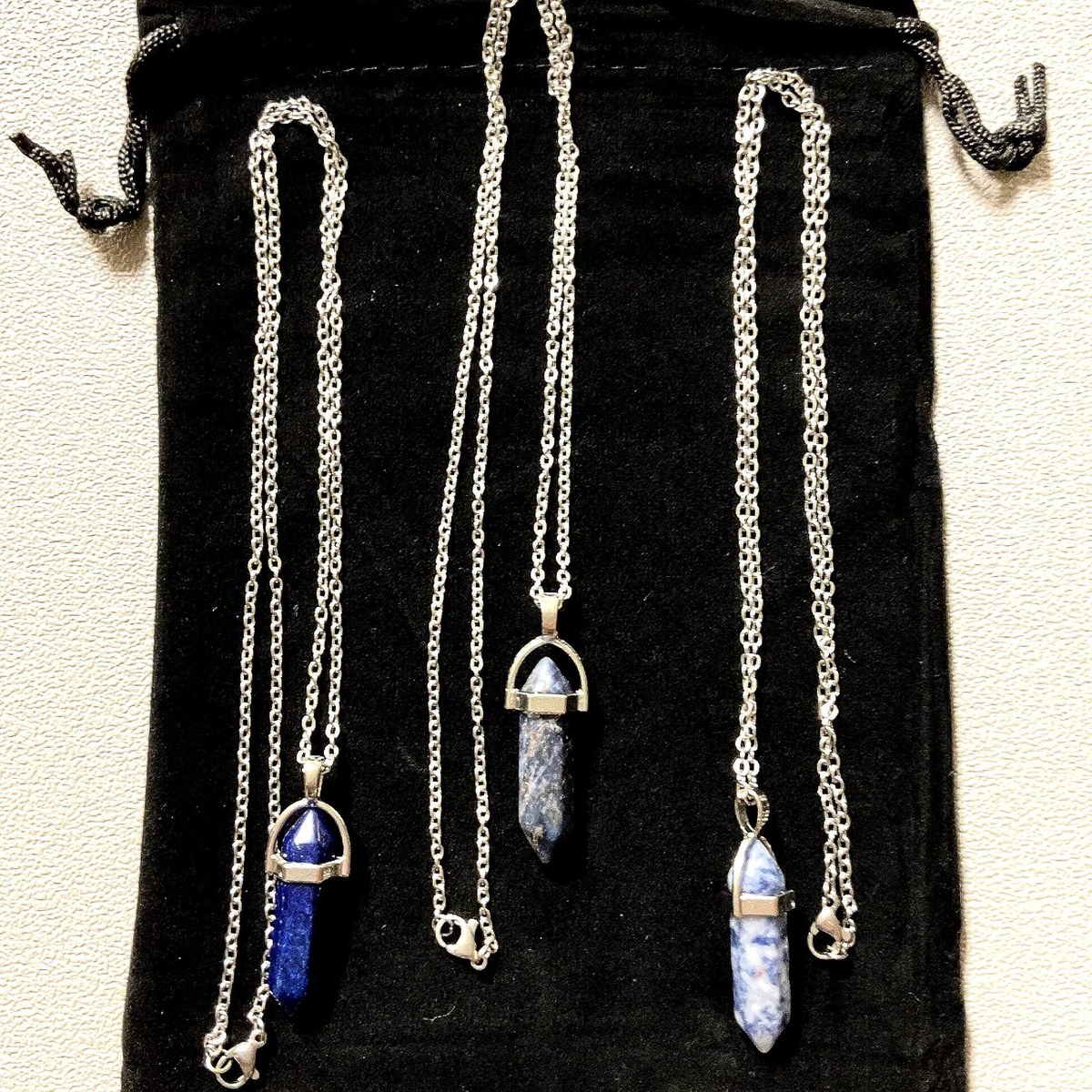 Set of three natural stone pendant necklaces on chains with a small gift bag