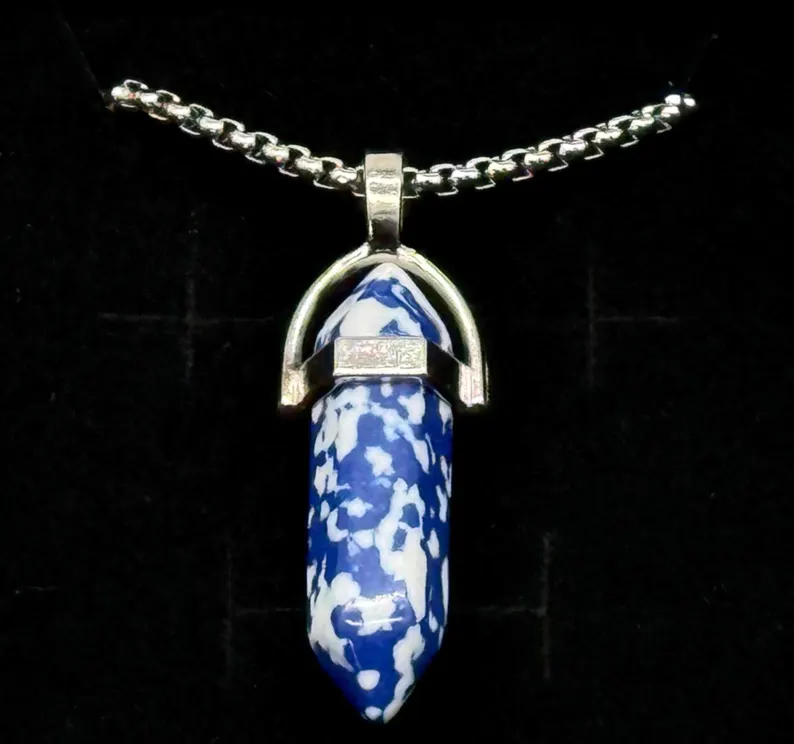 Macro close-up of a sodalite crystal point pendant showing blue and white mineral patterning