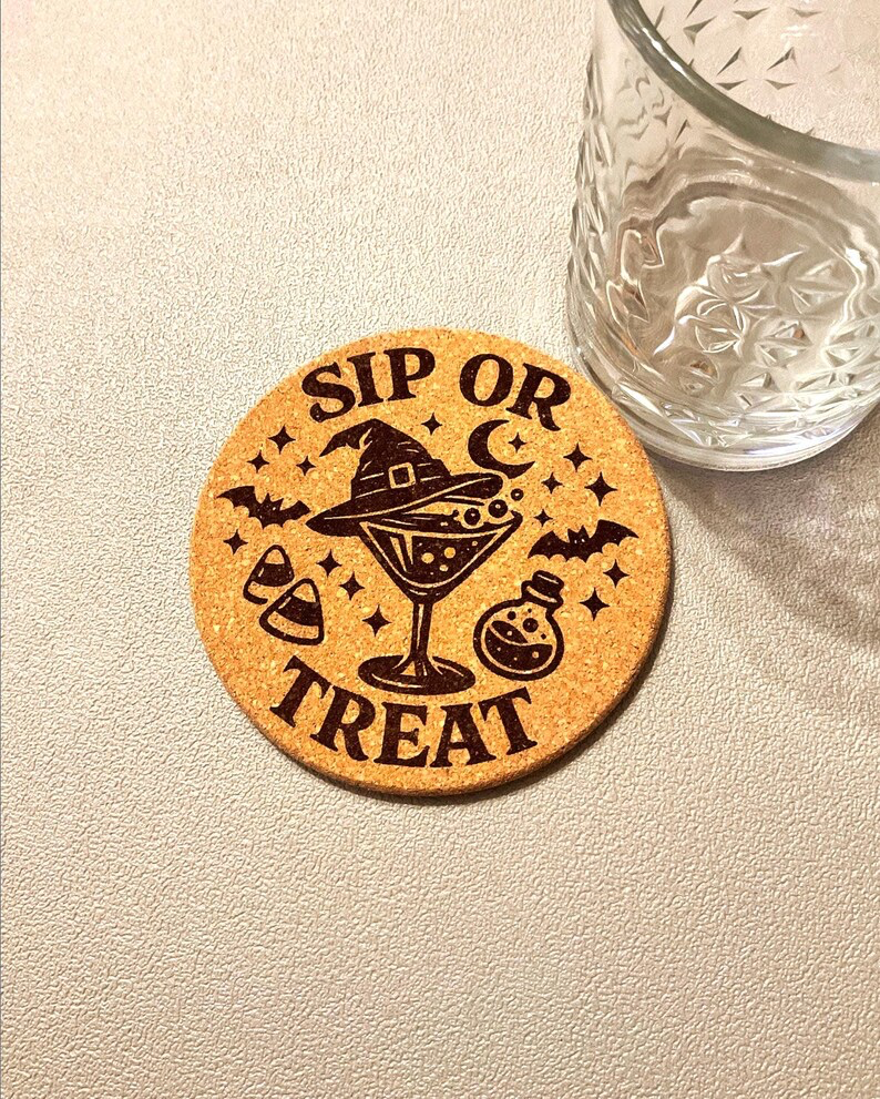 A single laser etched Sip or Treat cork coaster under a textured rocks glass, showing witch hat, martini, bats, candy corn, and potion bottle detail