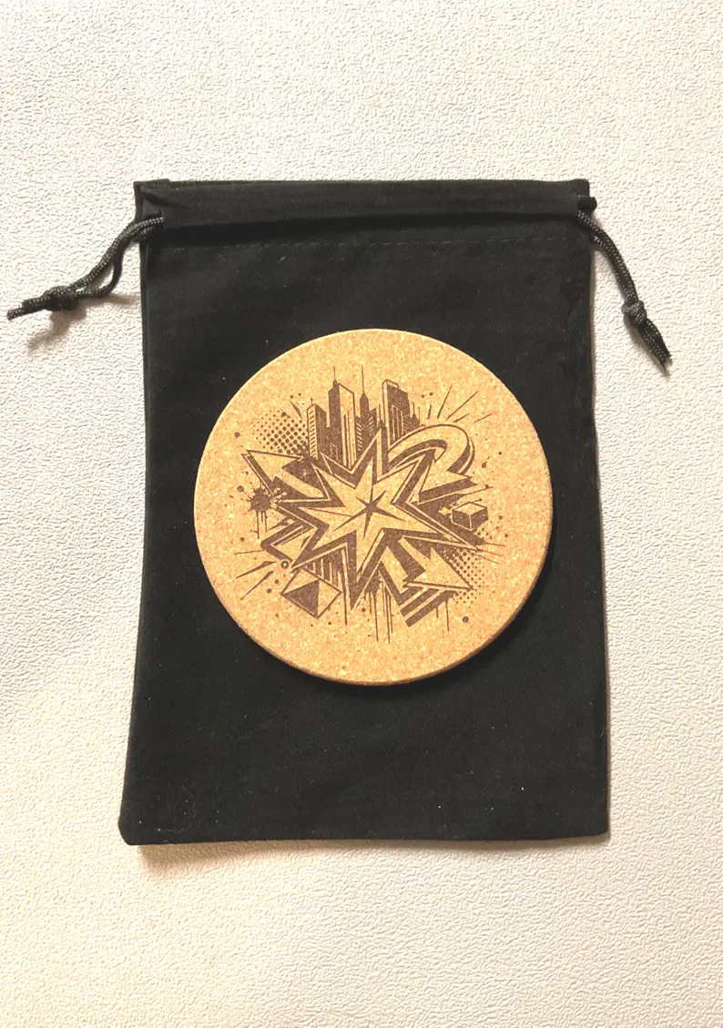 Laser engraved cityscape cork coaster resting on a black velvet drawstring gift pouch, ready to gift — custom cork coaster engraving by Robert Anthony Art in Vacaville, California
