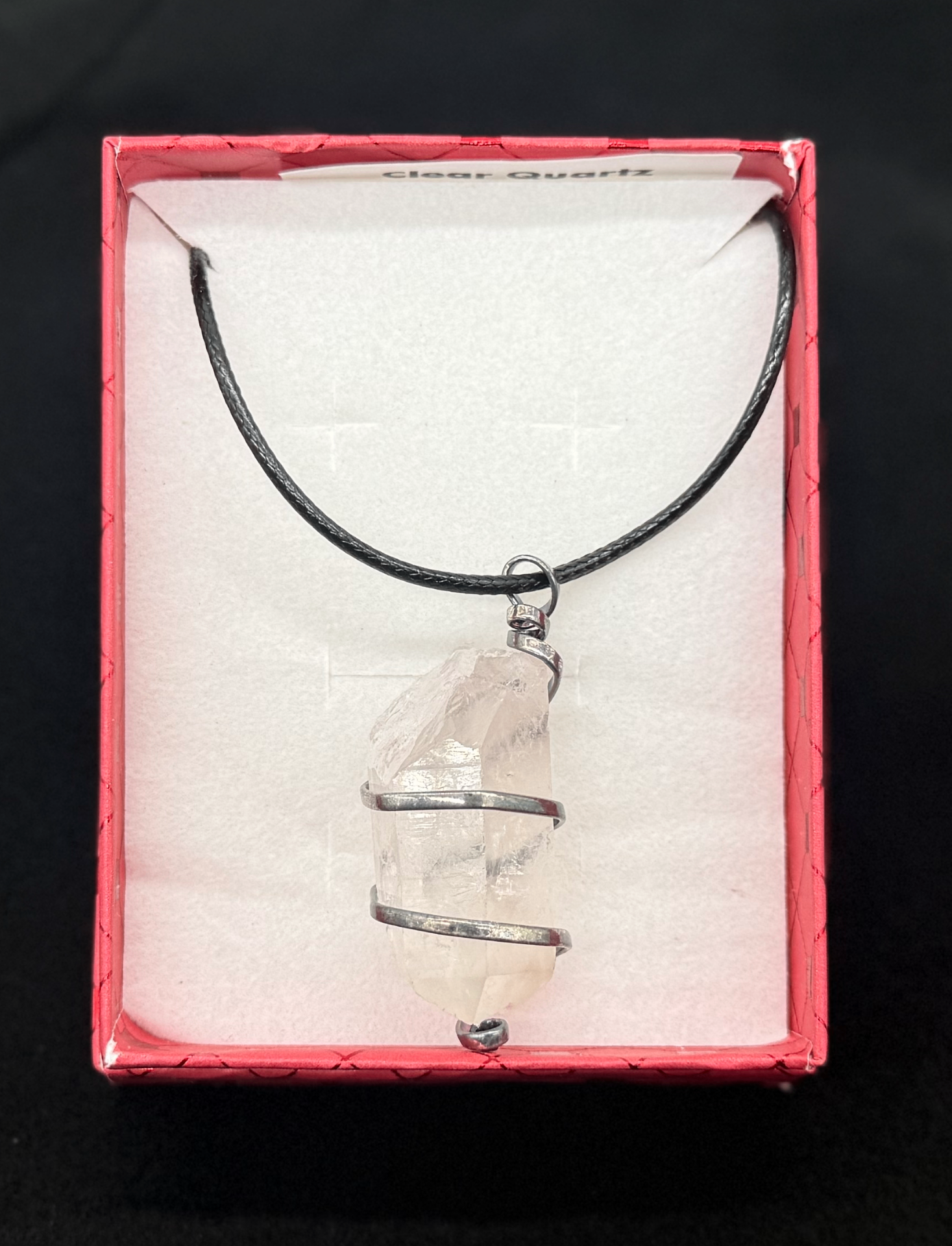 Raw clear quartz point pendant wrapped in silver wire, in a red gift box