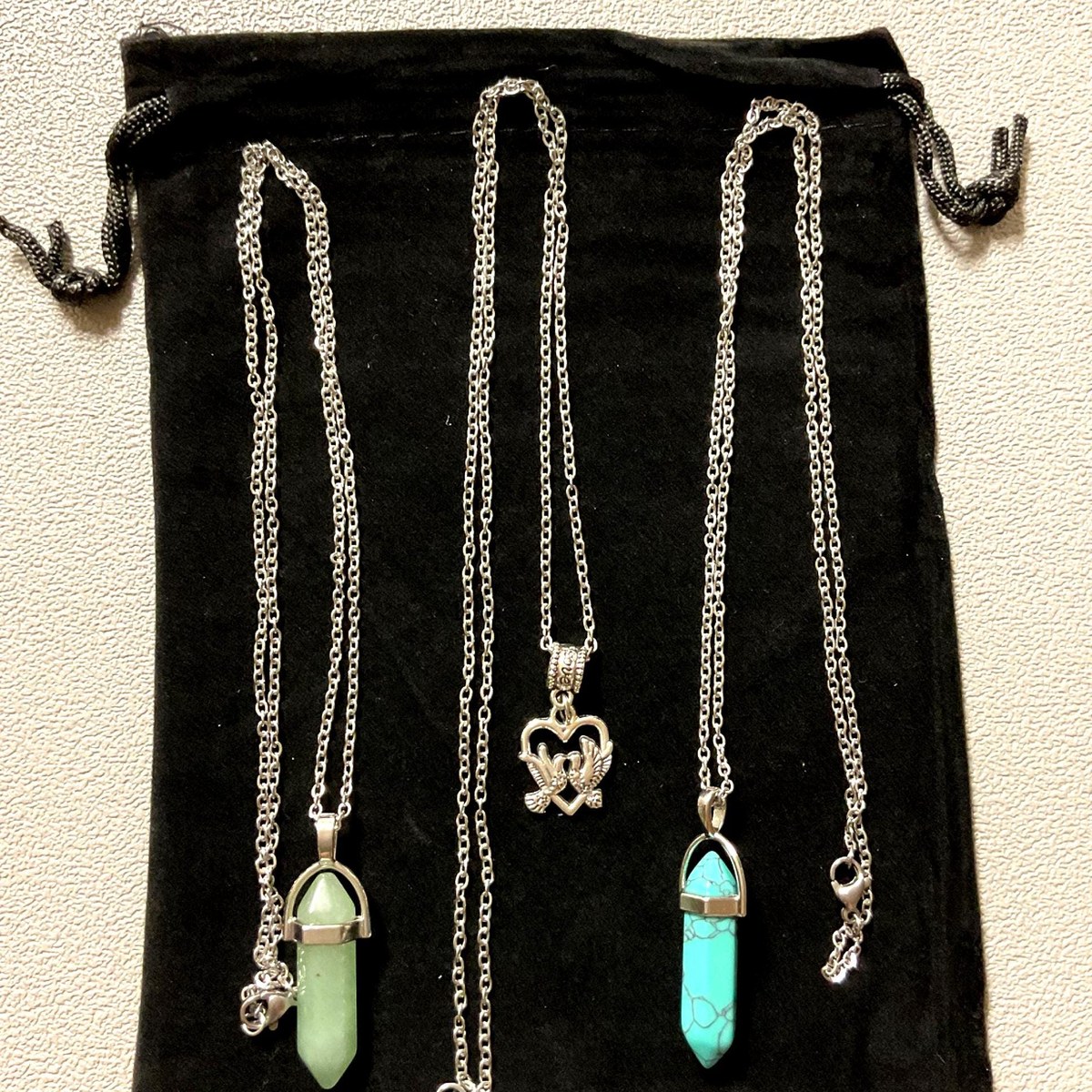 Set of three necklaces featuring stone and heart pendants arranged on a light surface