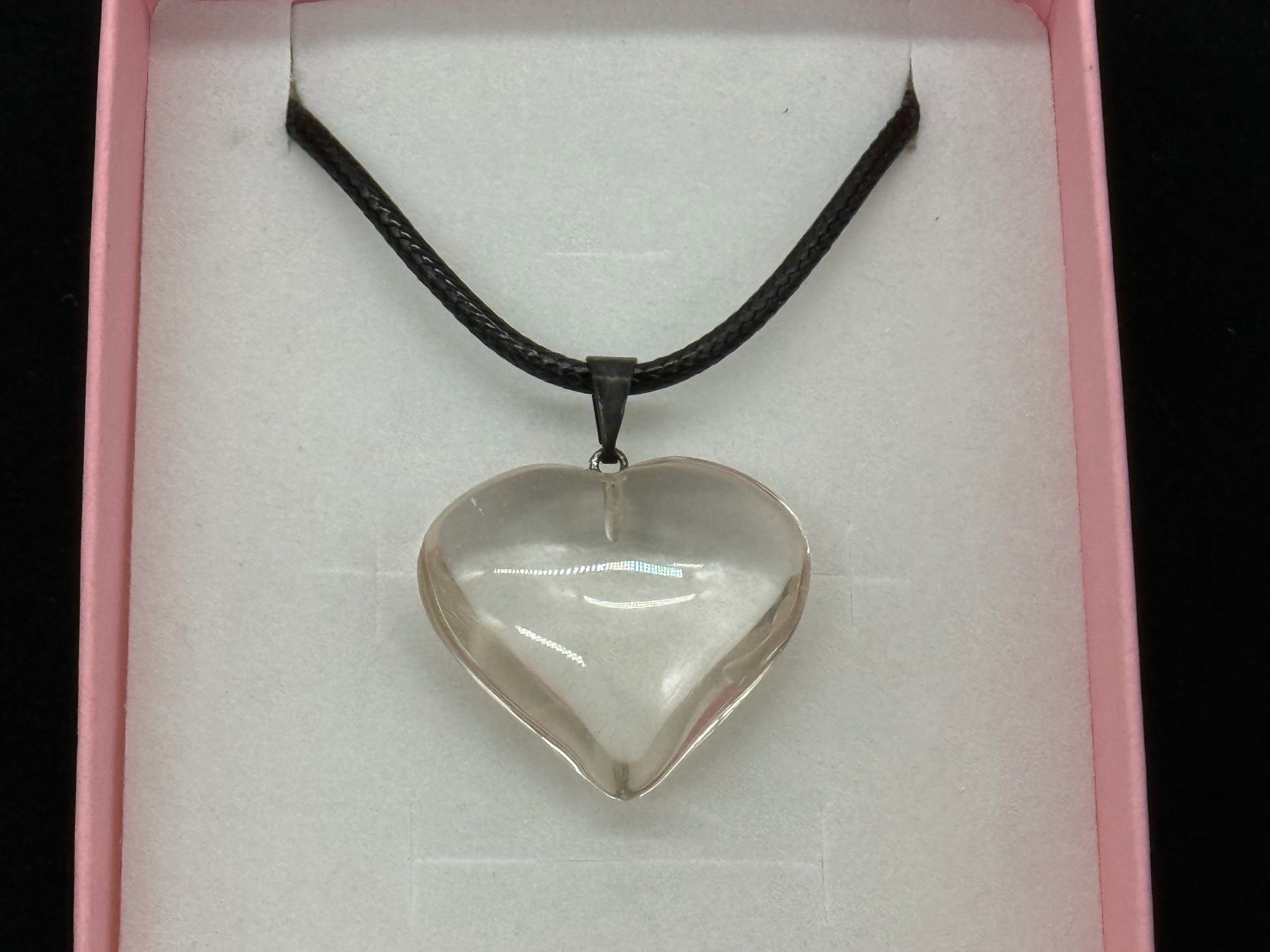 Polished clear quartz heart pendant on a black cord in a pink gift box, photographed in-studio by Robert and Angela Anthony