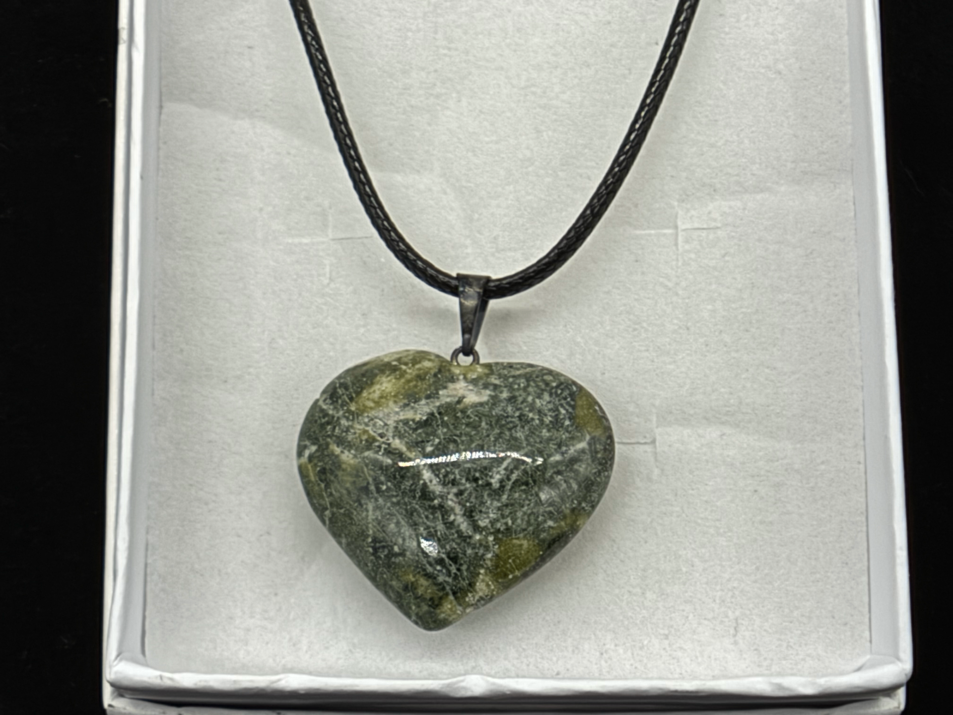 Polished green serpentine heart pendant on a black cord in a white gift box, photographed in-studio by Robert and Angela Anthony
