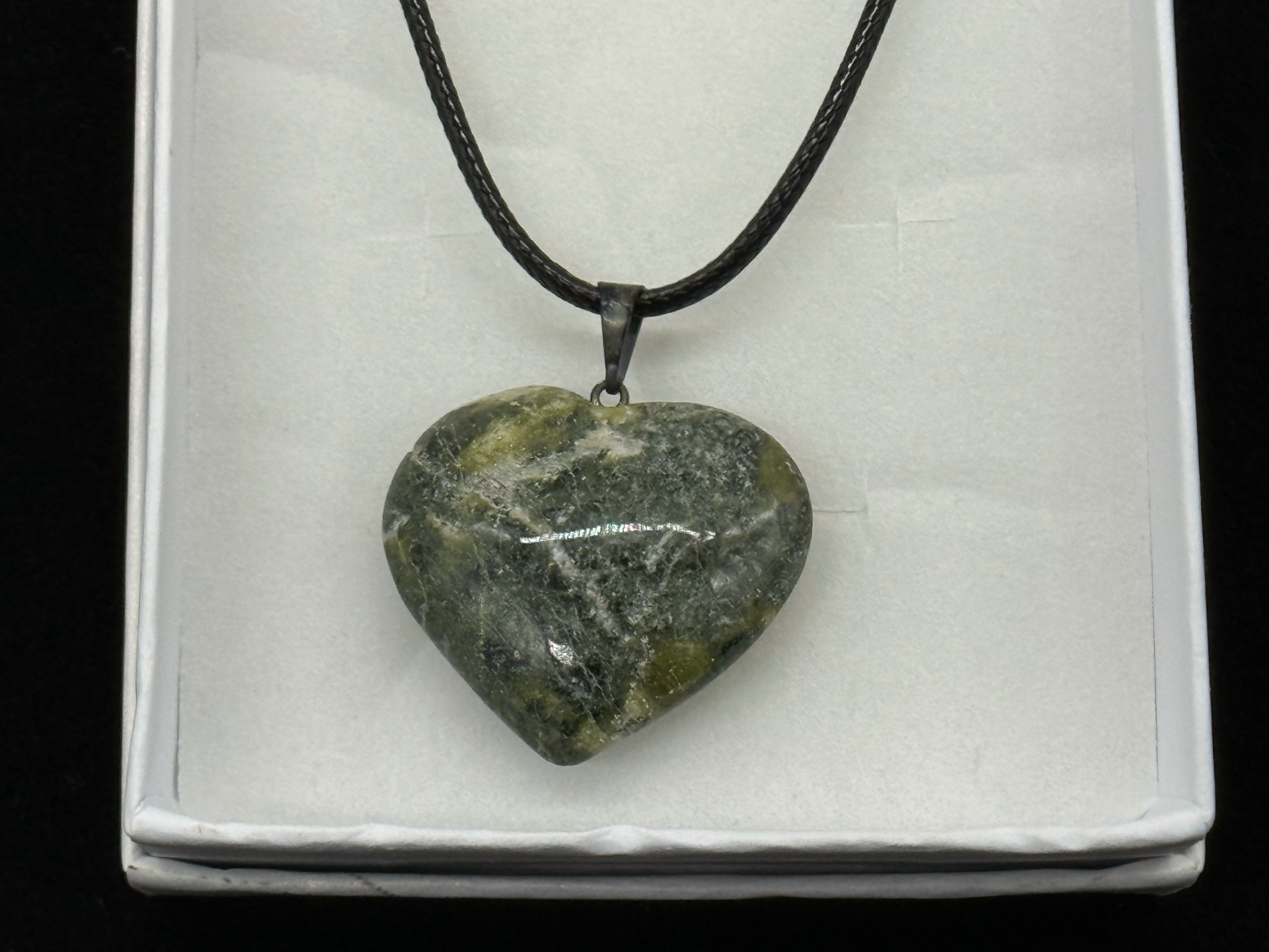 Polished green serpentine heart pendant on a black cord in a white gift box, photographed in-studio by Robert and Angela Anthony