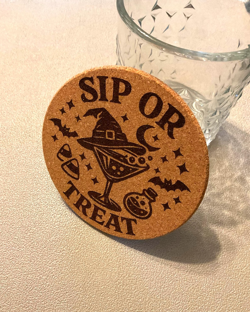 Close-up of a single laser etched cork coaster showing deep brown burn detail in the witch hat, martini glass, moon, and Sip or Treat lettering